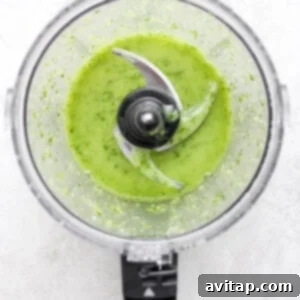 A food processor filled with a vibrant green herby dressing.