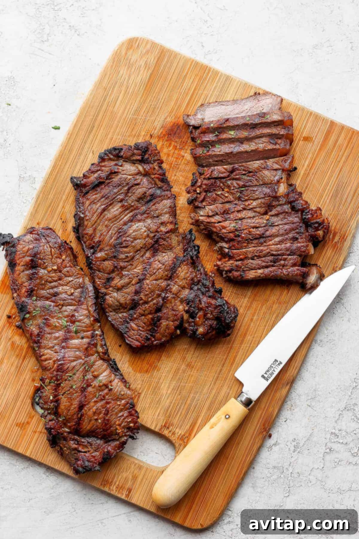 Perfectly cooked, sliced New York strip steak on a wooden cutting board.