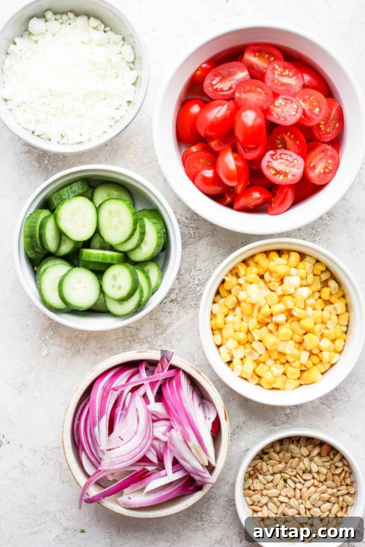 Bowls filled with individual steak salad ingredients: romaine, corn, tomatoes, avocado, and red onion.