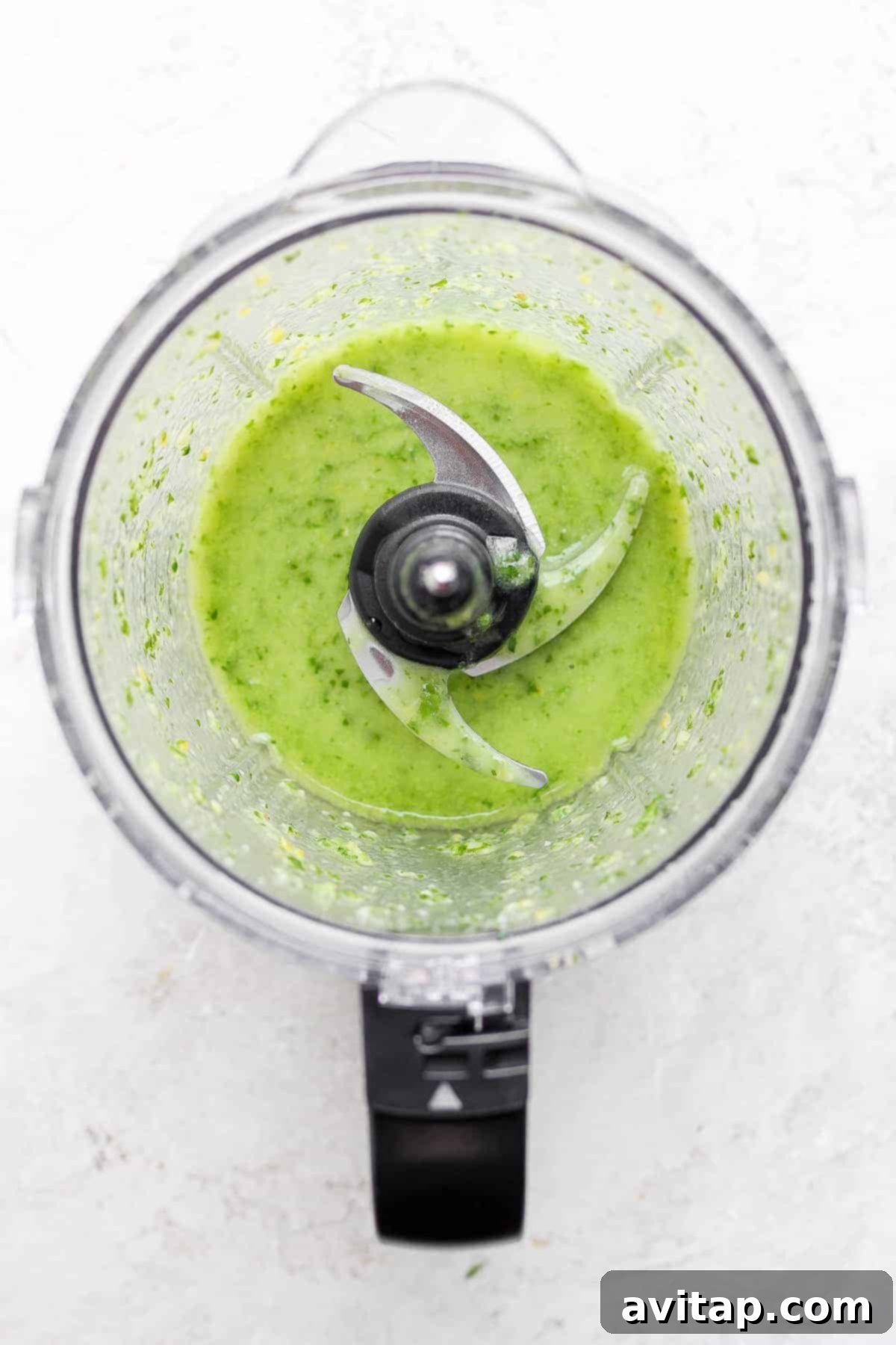 Steak salad dressing being blended in a food processor, a vibrant green mixture.