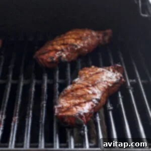 Steak grilling on a hot barbecue, showing grill marks.