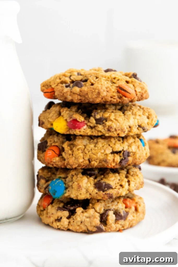 The ultimate flourless Monster Cookies, loaded with peanut butter, oats, chocolate chips, and M&M's for an irresistible treat. Stack of freshly baked flourless monster cookies, showcasing their chewy texture and vibrant mix-ins of chocolate chips and M&M's.