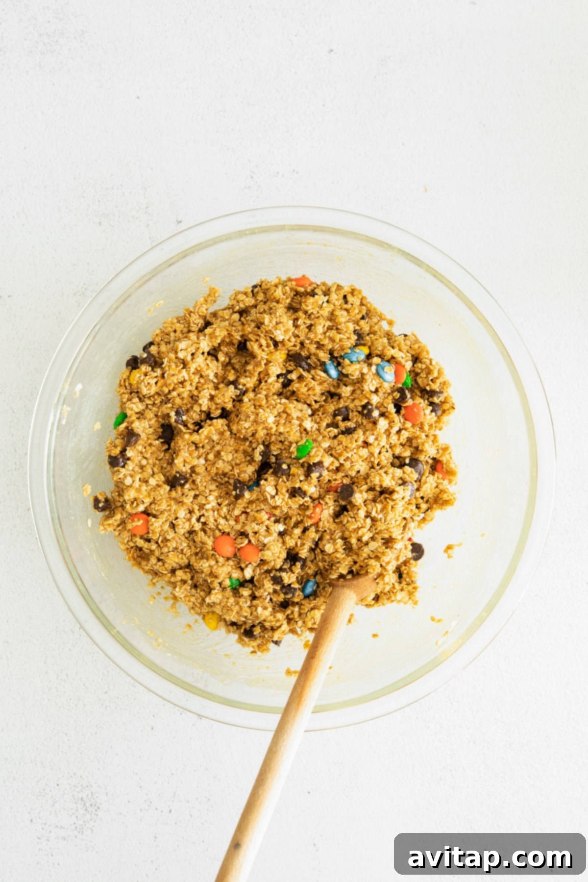 Perfectly portioned monster cookie dough balls, eager to be transformed into golden, chewy delights. Scoops of rich monster cookie dough ready for baking, showcasing its hearty texture with visible oats, chocolate, and M&M's mixed in.