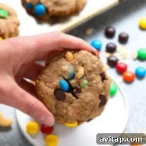 Epic Flourless Monster Cookies 2 Hand holding a freshly baked vegan monster cookie, showcasing its rustic texture and vibrant mix-ins.