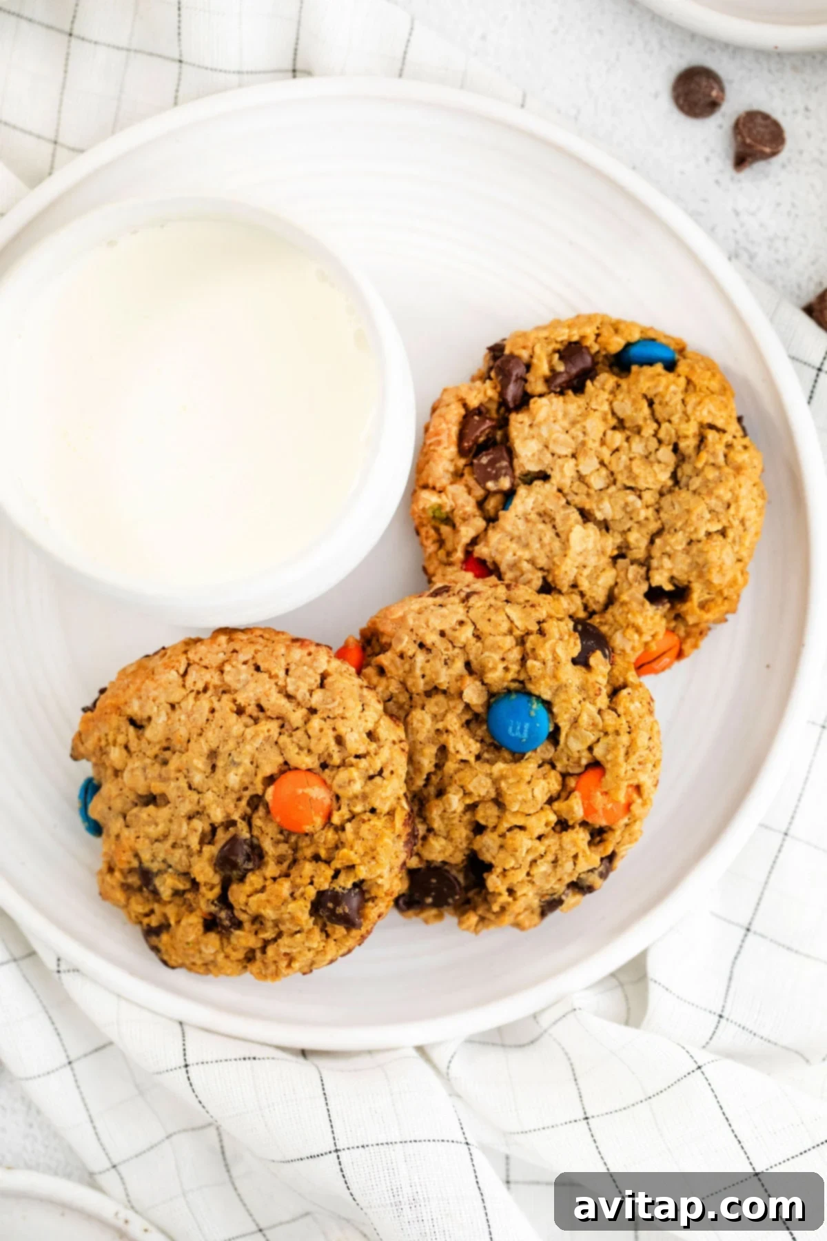 A trio of irresistible monster cookies, showcasing their perfect texture and colorful additions. Three perfectly chewy flourless monster cookies beautifully arranged on a white plate, ready to be enjoyed as a delightful treat.