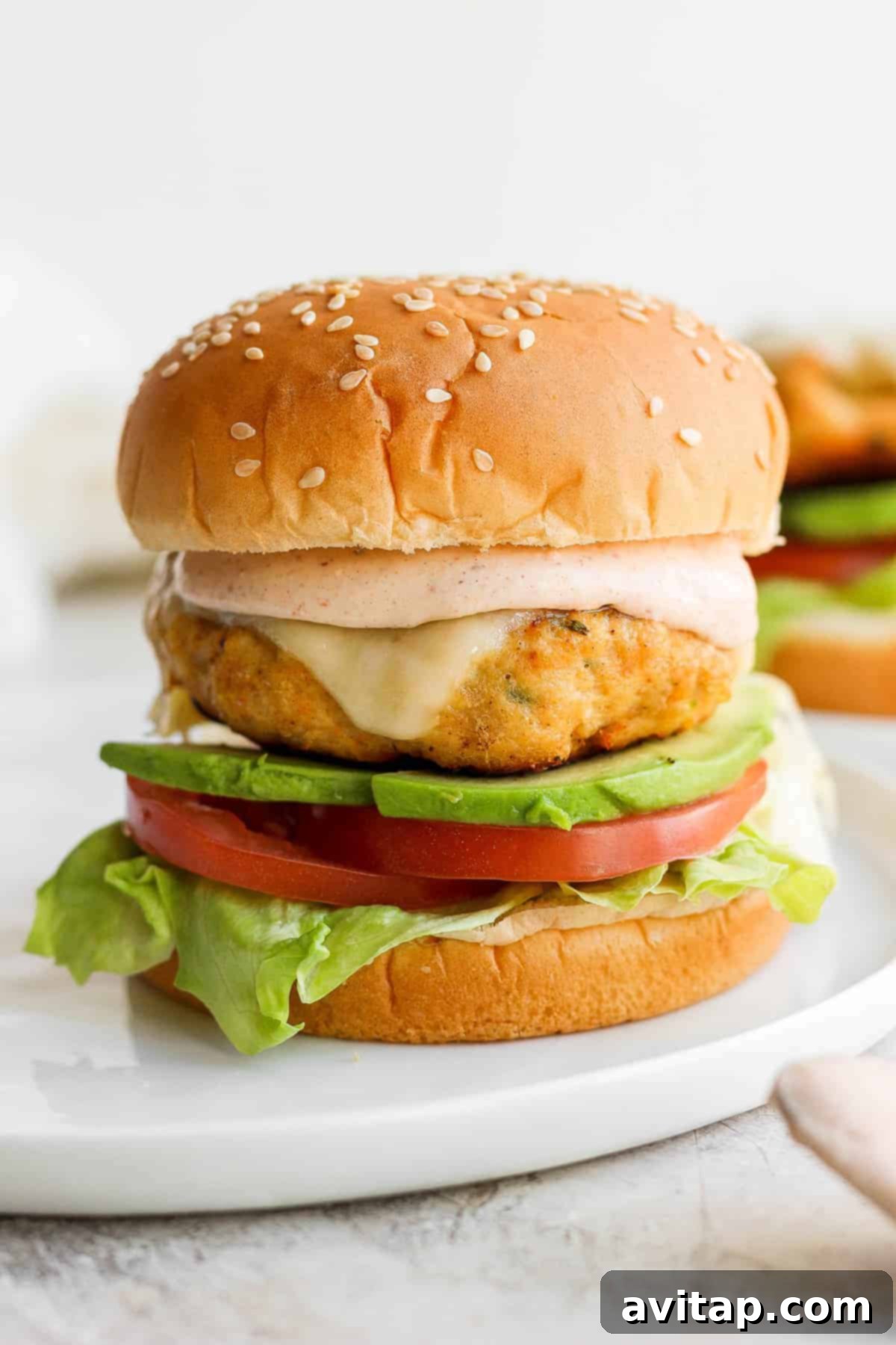 Assembled chicken burger with our secret sauce on a toasted bun, presented on a plate.