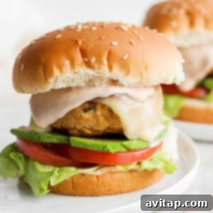 Fully assembled chicken burger on a plate, ready to be topped with the bun.