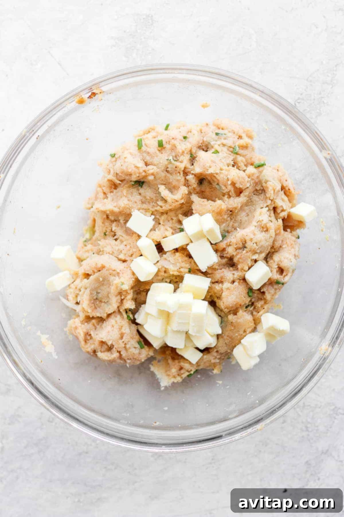 Burger meat mixture and cold butter cubes in a large mixing bowl, ready to be combined for patties.