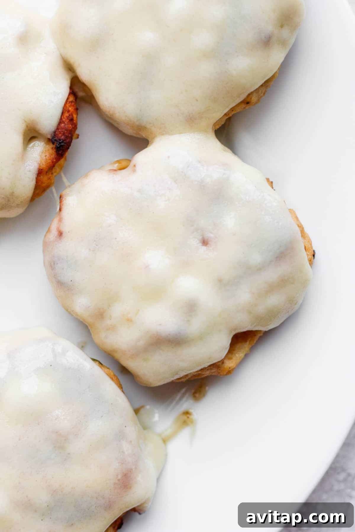 Melted Swiss cheese perfectly draped over a grilled chicken burger patty on a bun.