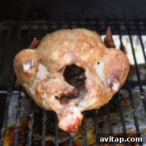 A whole chicken smoking on a pellet grill.