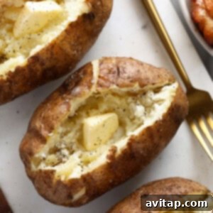 Three perfectly smoked baked potatoes on a plate with a fork inserted into one, ready to be eaten or topped.