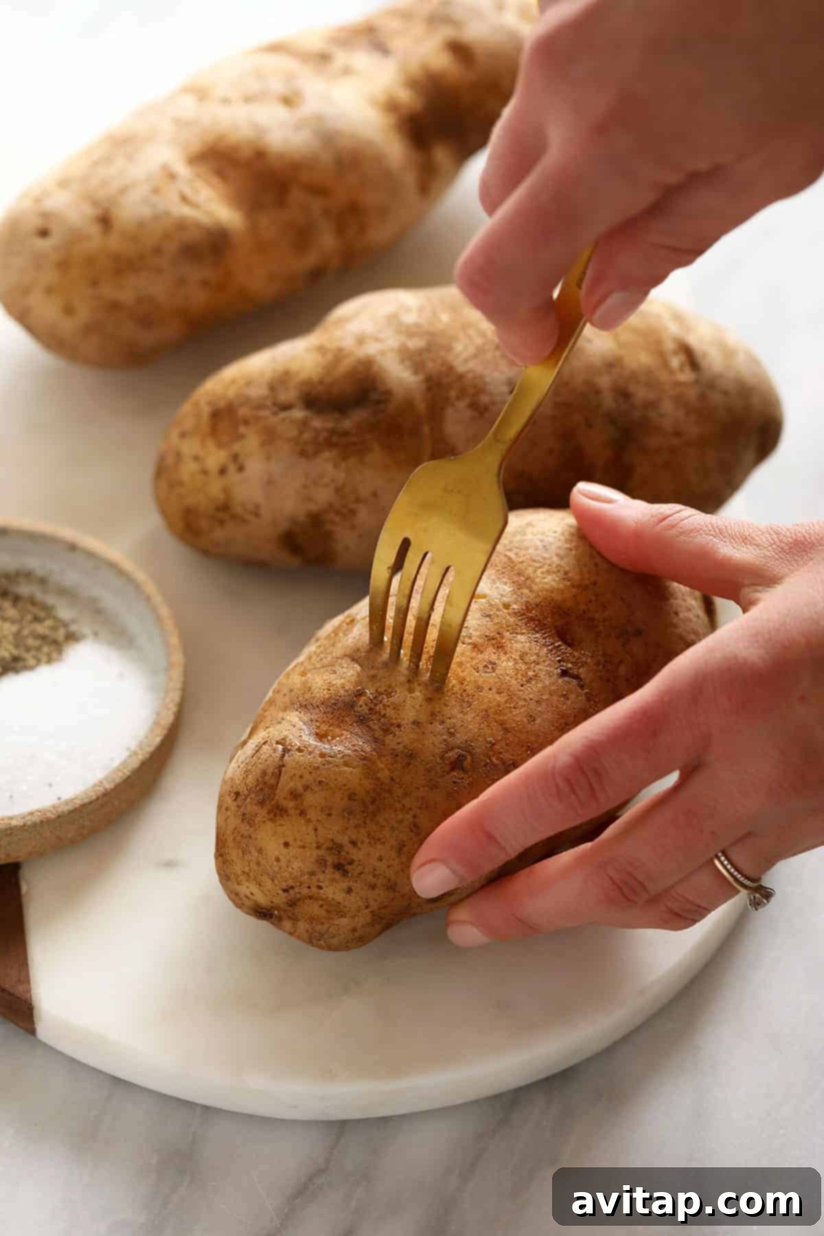 A hand gently poking several holes into a raw Russet potato with a fork, a crucial step before seasoning and smoking.