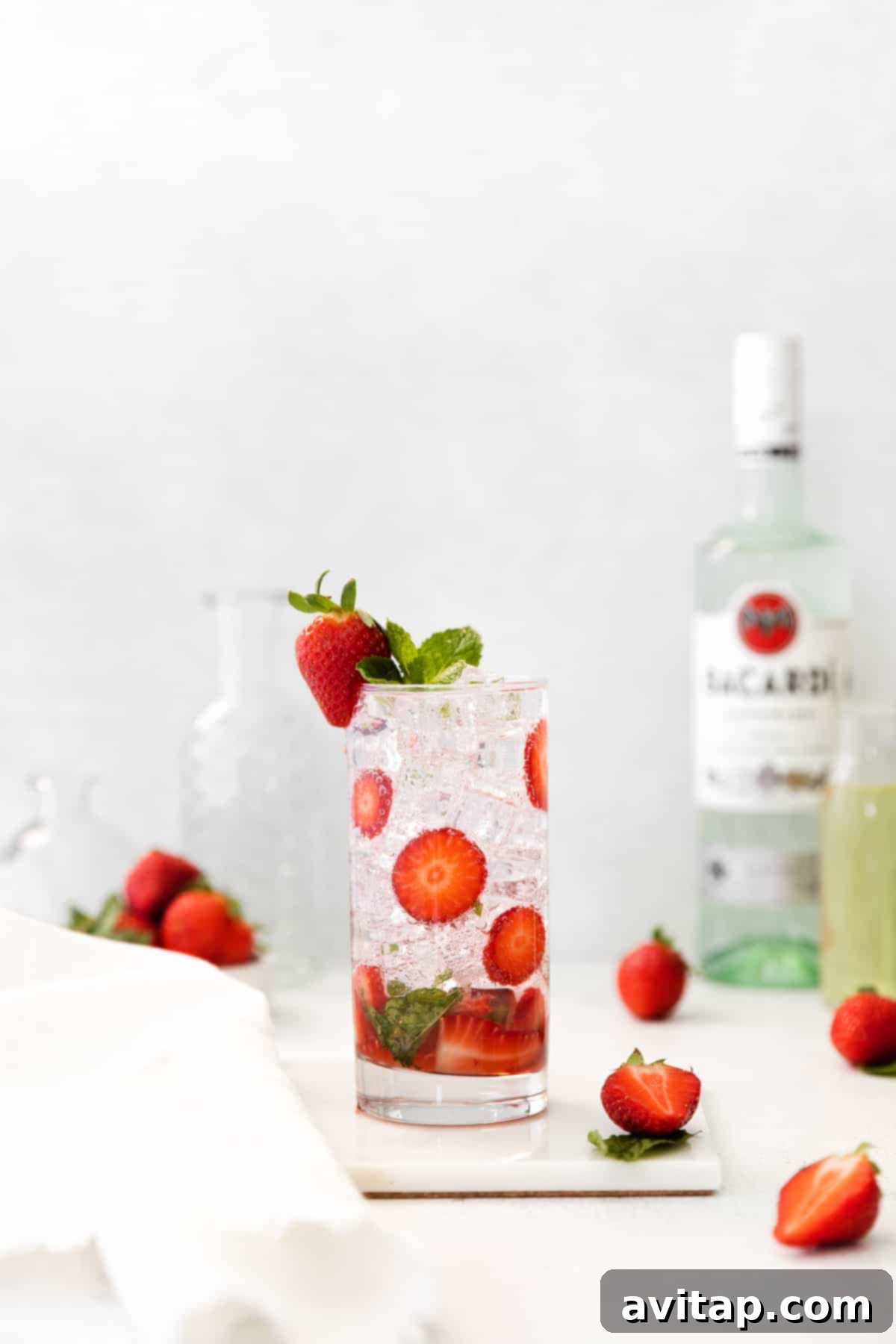 Close-up of a strawberry mojito in a clear glass with ice and garnishes