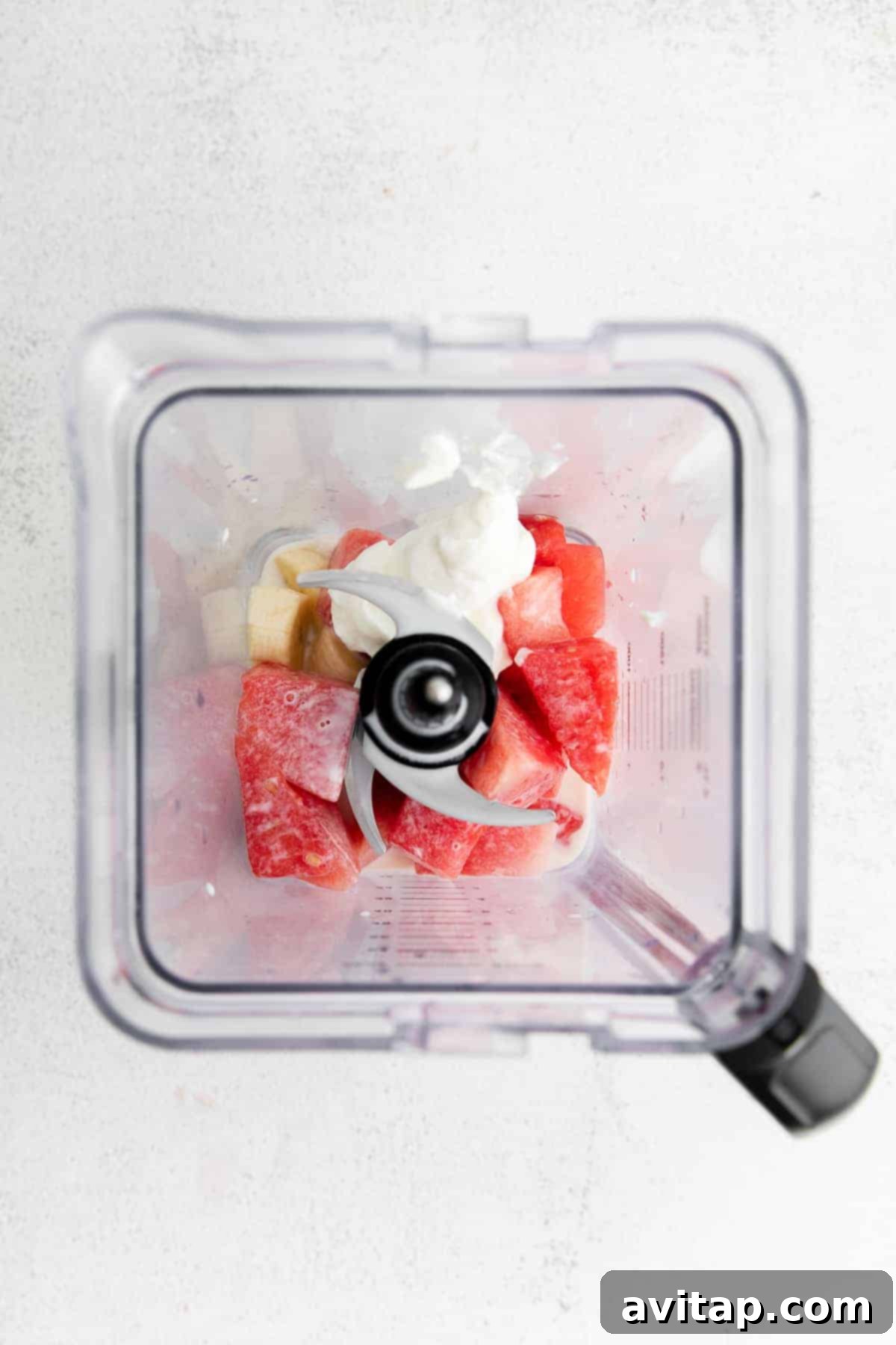 All the vibrant ingredients for the watermelon smoothie – frozen watermelon, strawberries, banana, yogurt, and milk – loaded into a high-speed blender, ready to be transformed.