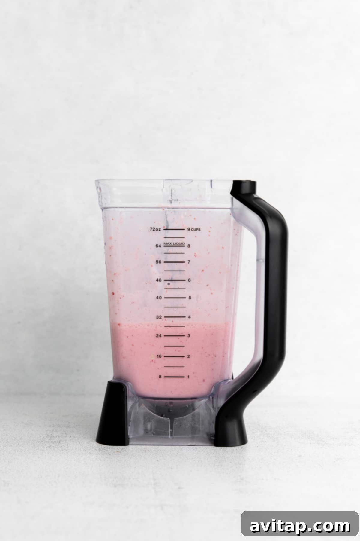 A creamy, pink watermelon smoothie swirling inside a blender, showcasing its smooth texture.