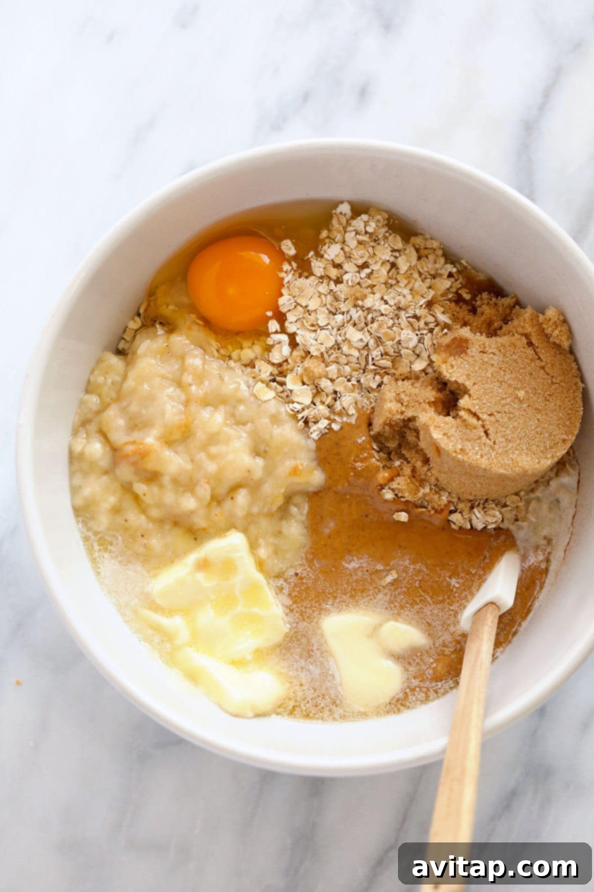 A bowl filled with freshly baked, chewy Peanut Butter Banana Oatmeal Cookies, featuring visible dark chocolate chunks.