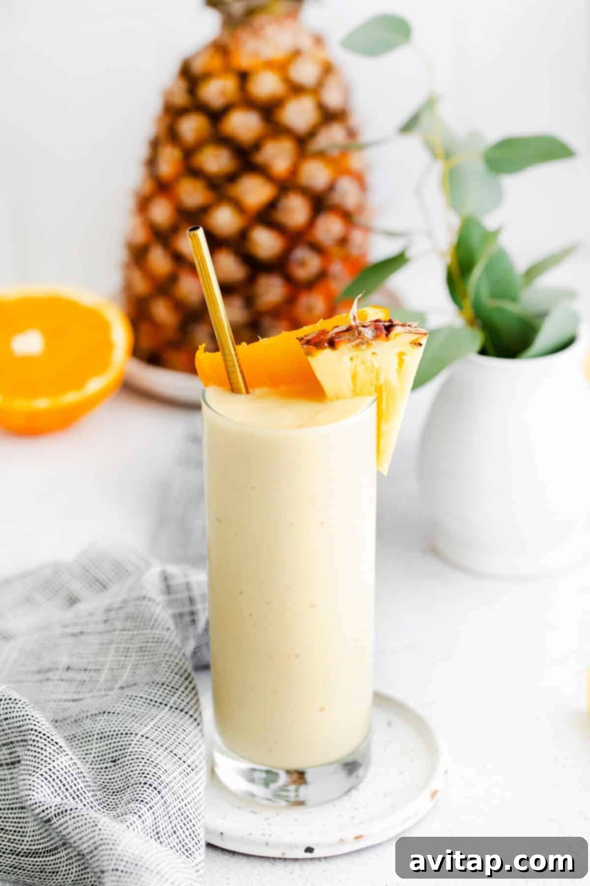 Vibrant pineapple smoothie garnished with orange and pineapple chunks, evoking a tropical vacation feel.