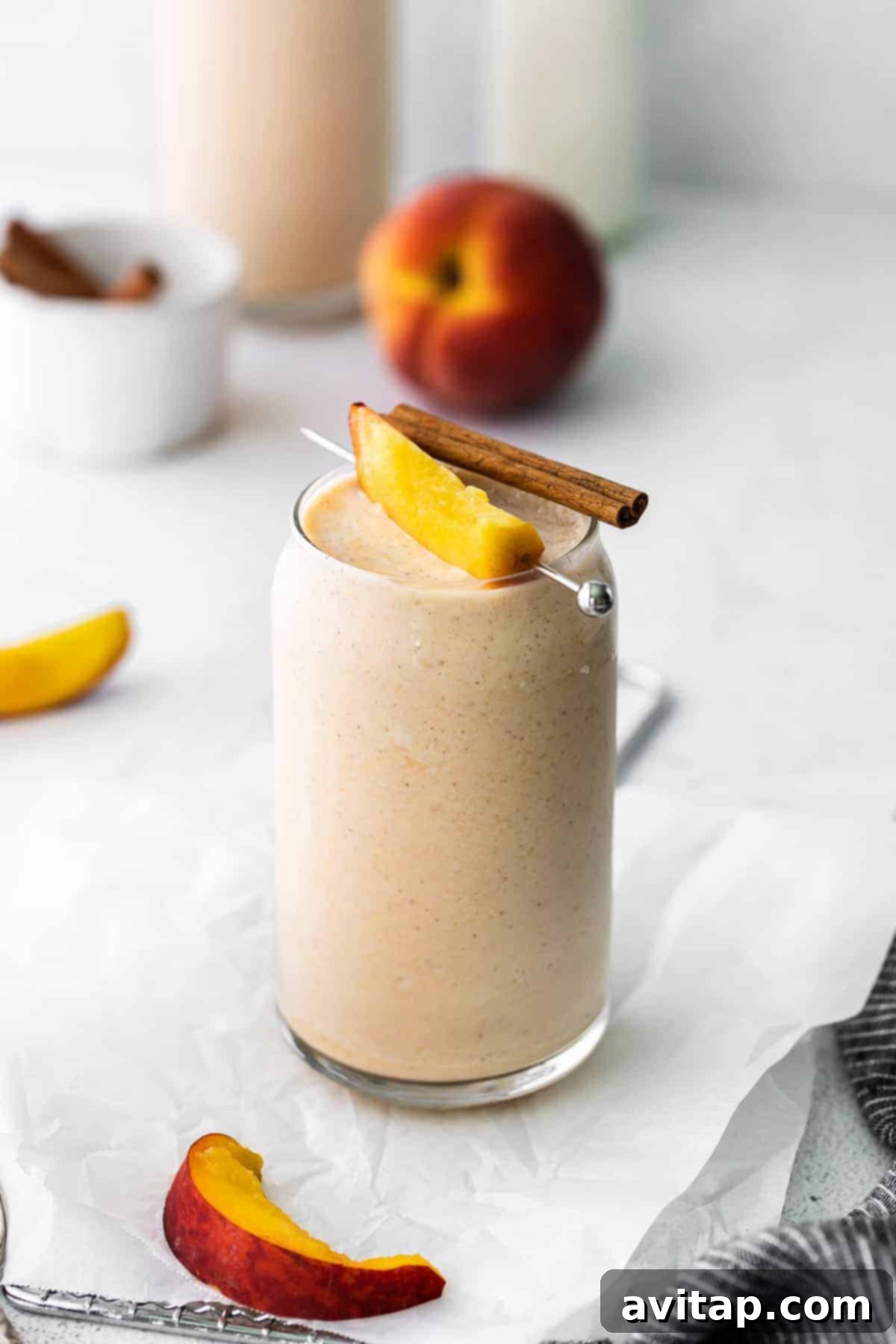 Get peachy with this simple peach smoothie recipe! This smoothie tastes just like a peach pie because it has hints of ground cinnamon and is so delicious. Vibrant peach smoothie garnished with fresh peach slices and a cinnamon stick, served in a glass