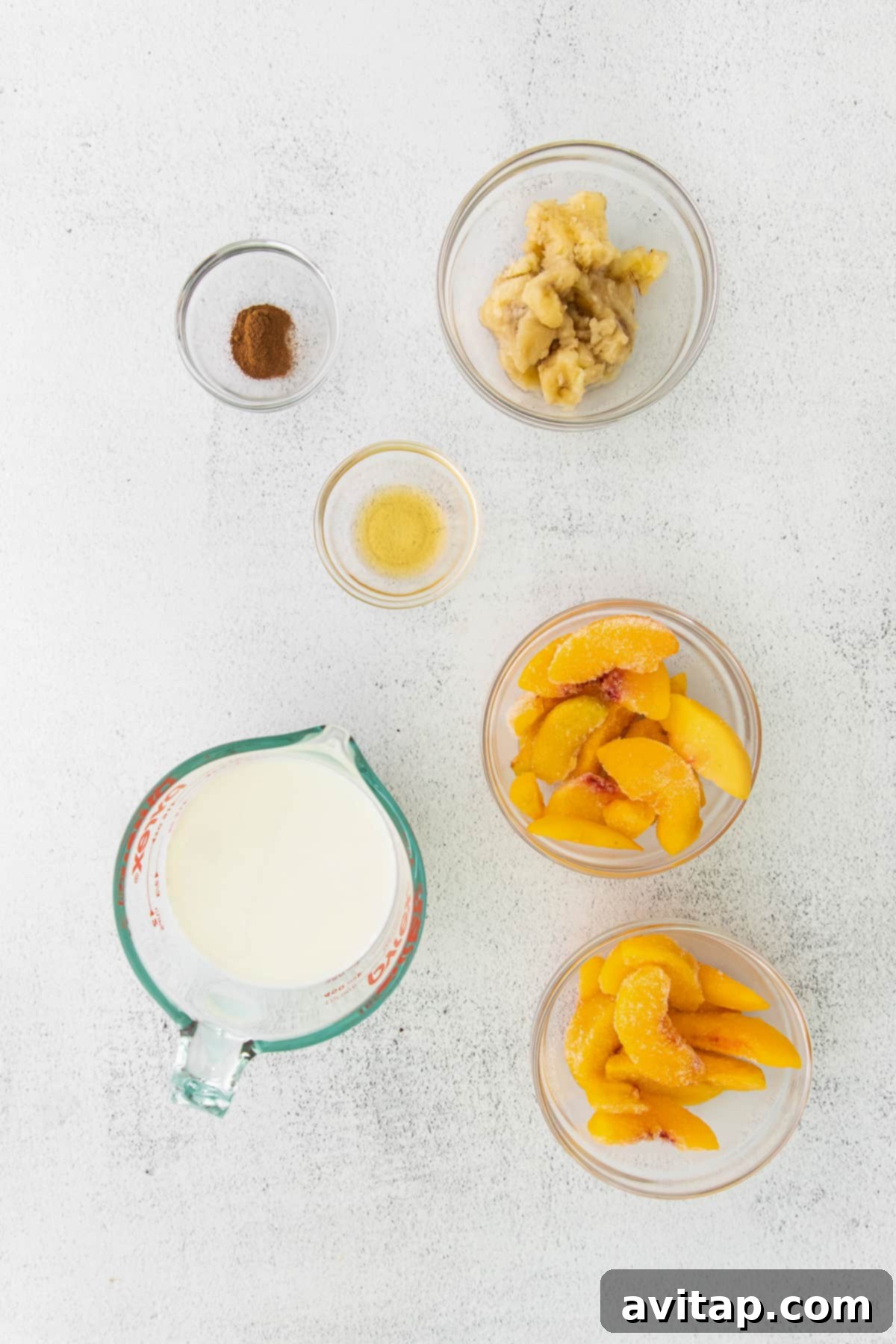Get peachy with this simple peach smoothie recipe! This smoothie tastes just like a peach pie because it has hints of ground cinnamon and is so delicious. A selection of fresh and frozen smoothie ingredients including peaches, bananas, cinnamon, and almond milk laid out on a kitchen counter