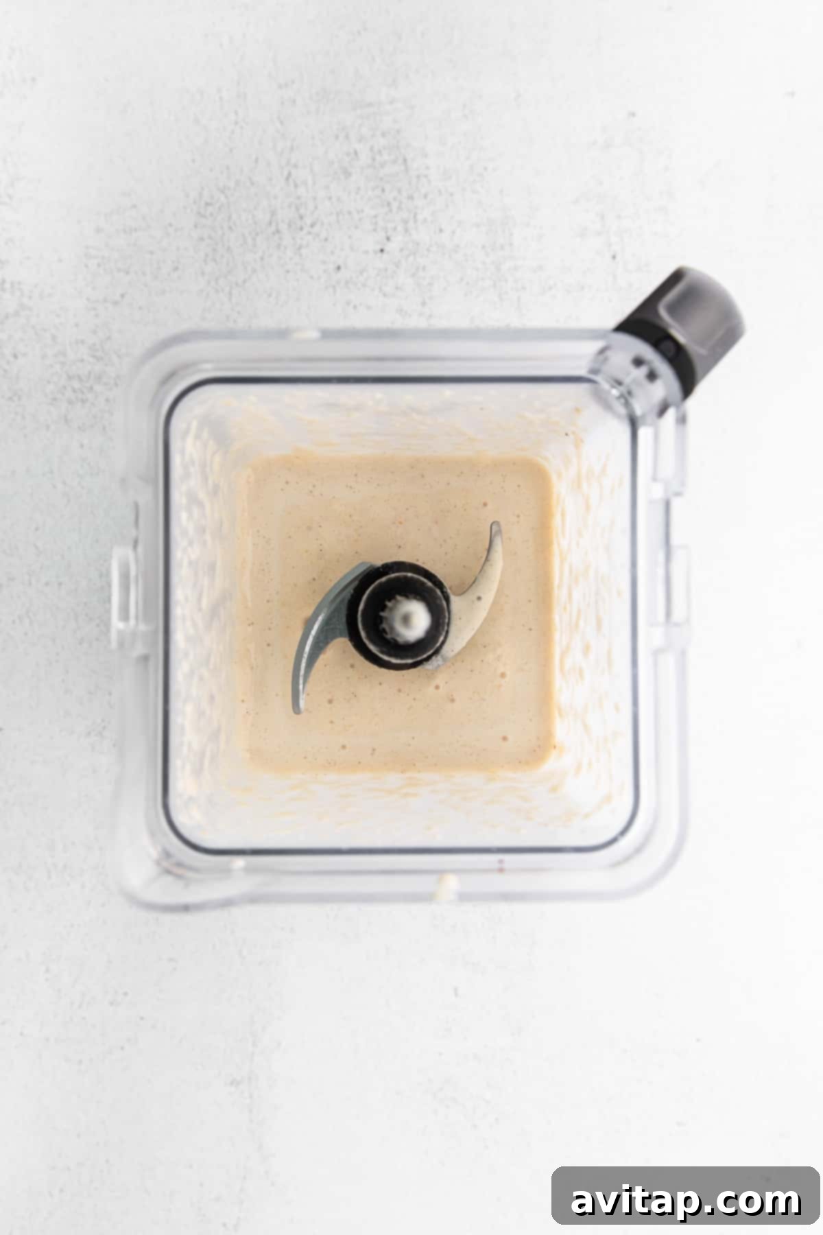 This peach smoothie tastes just like dessert, but it's healthy and made with just 5 ingredients. Make this smoothie all summer long with frozen peaches, banana, cinnamon, almond milk, and vanilla. A creamy peach smoothie being poured into a glass from a blender, showing its smooth texture