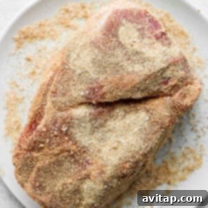 A seasoned pork shoulder roast ready for cooking, showcasing the dry rub application.