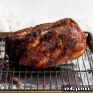 A BBQ pork roast resting on a wire rack over a baking sheet, after searing.