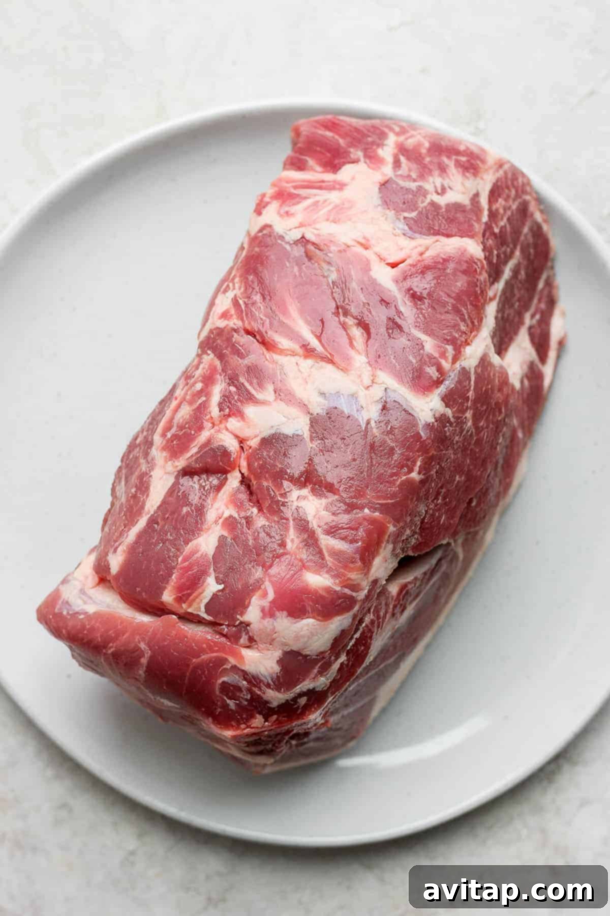 Cooked slow roasted pork shoulder, beautifully browned and resting on a plate.