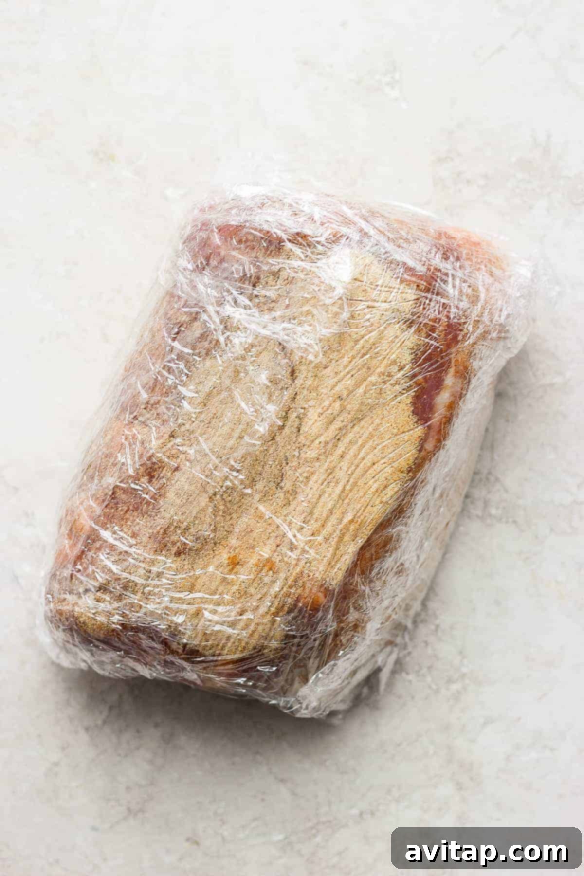 Prepping Pork Shoulder: Dry Rub Overnight A dry-rubbed pork shoulder wrapped tightly in plastic wrap, ready for refrigeration.