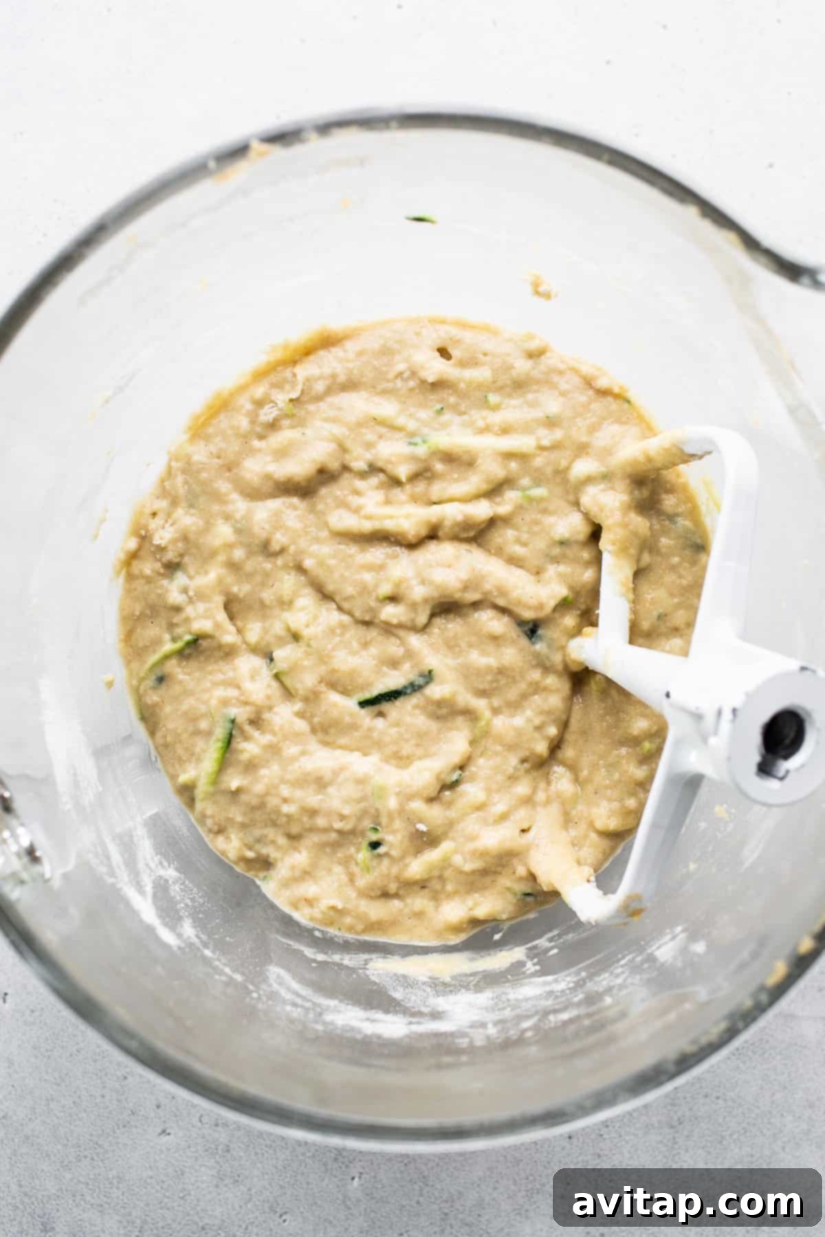 A food processor containing freshly grated zucchini, demonstrating the first step in preparing zucchini for baking.