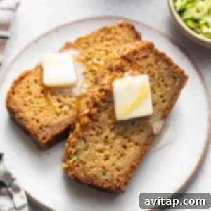 Two slices of moist zucchini bread with butter on a plate, ready to be enjoyed.