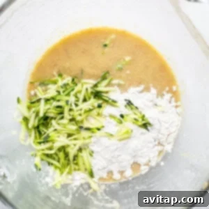 A large mixing bowl containing the combined wet and dry ingredients with shredded zucchini, ready for baking into a delicious loaf.