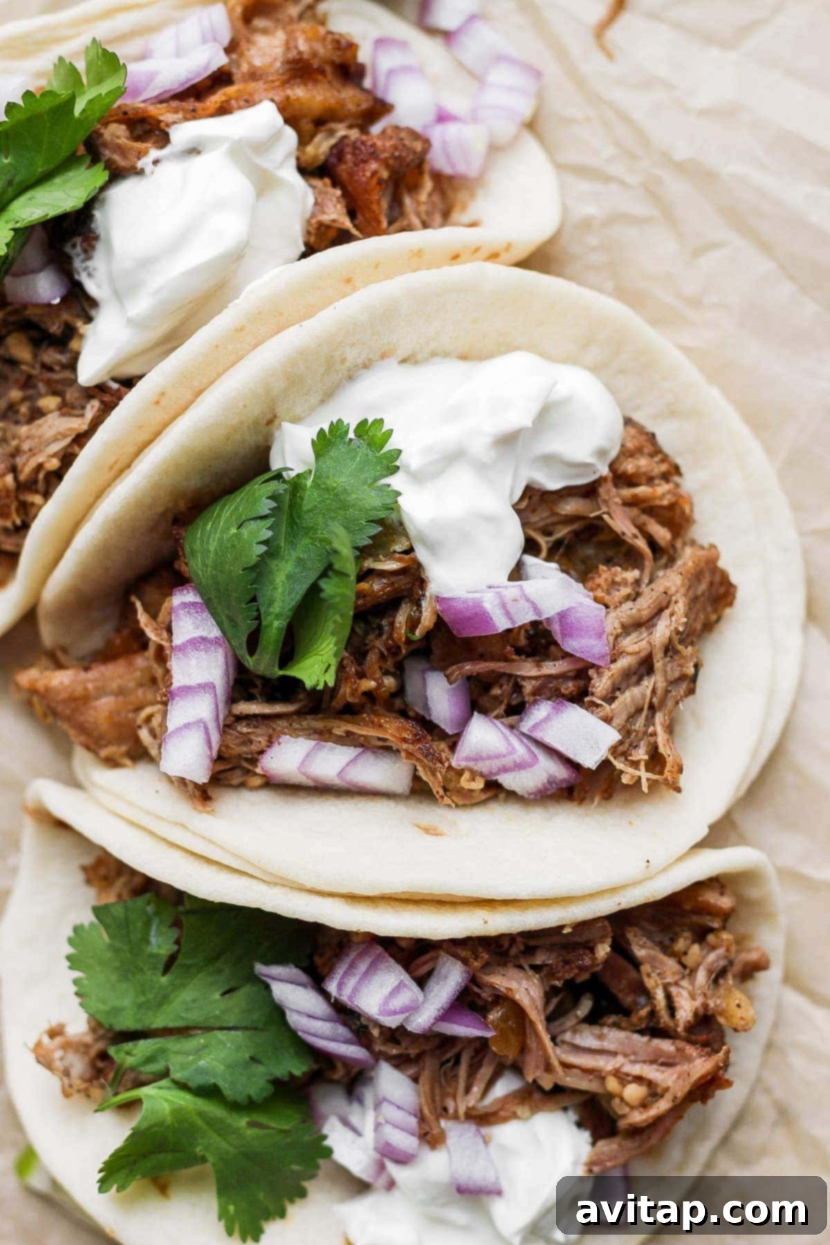 Crispy carnitas tacos topped with Greek yogurt, minced red onion, and fresh cilantro