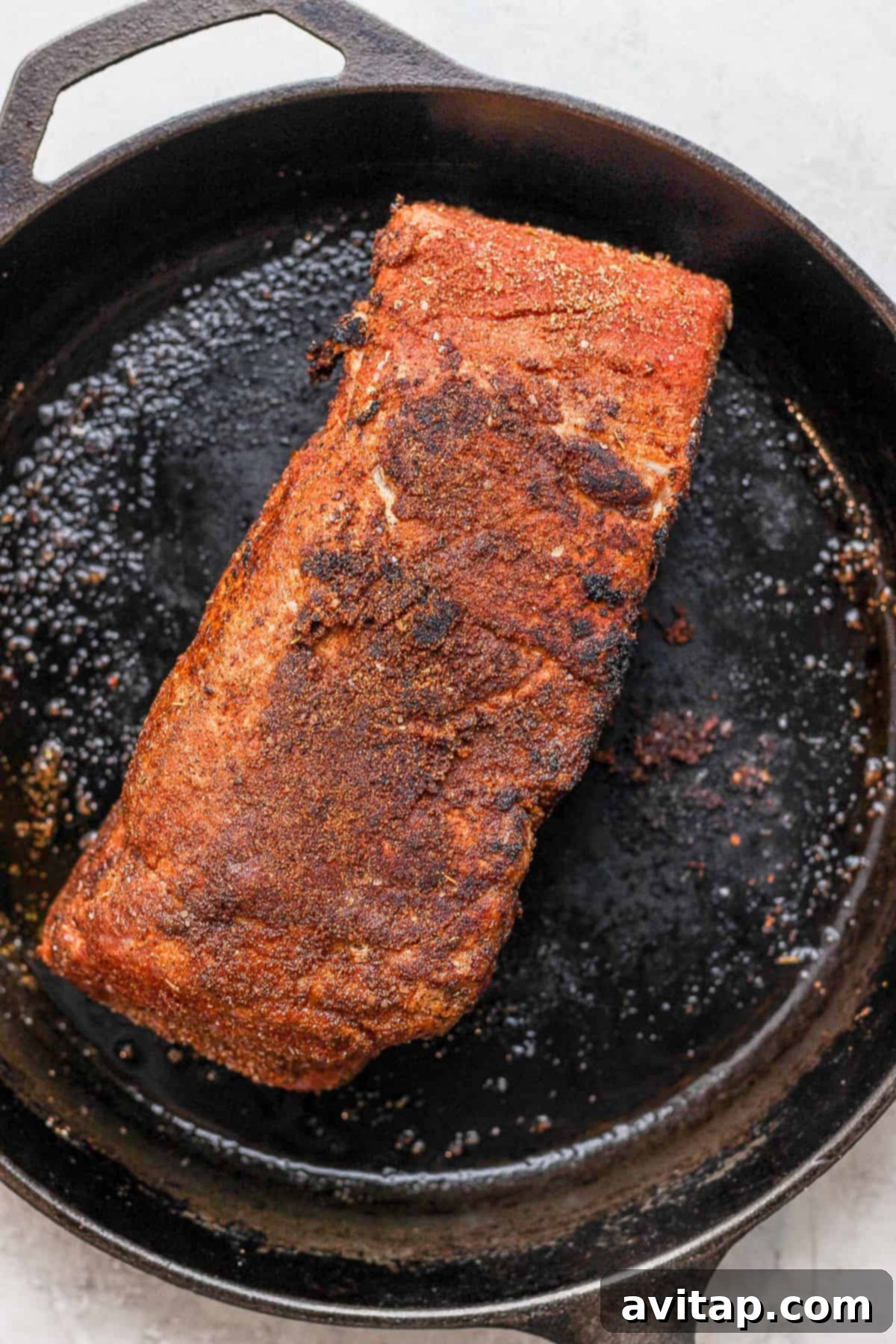 Pork shoulder being seared in a cast iron skillet, developing a crispy, flavorful crust.