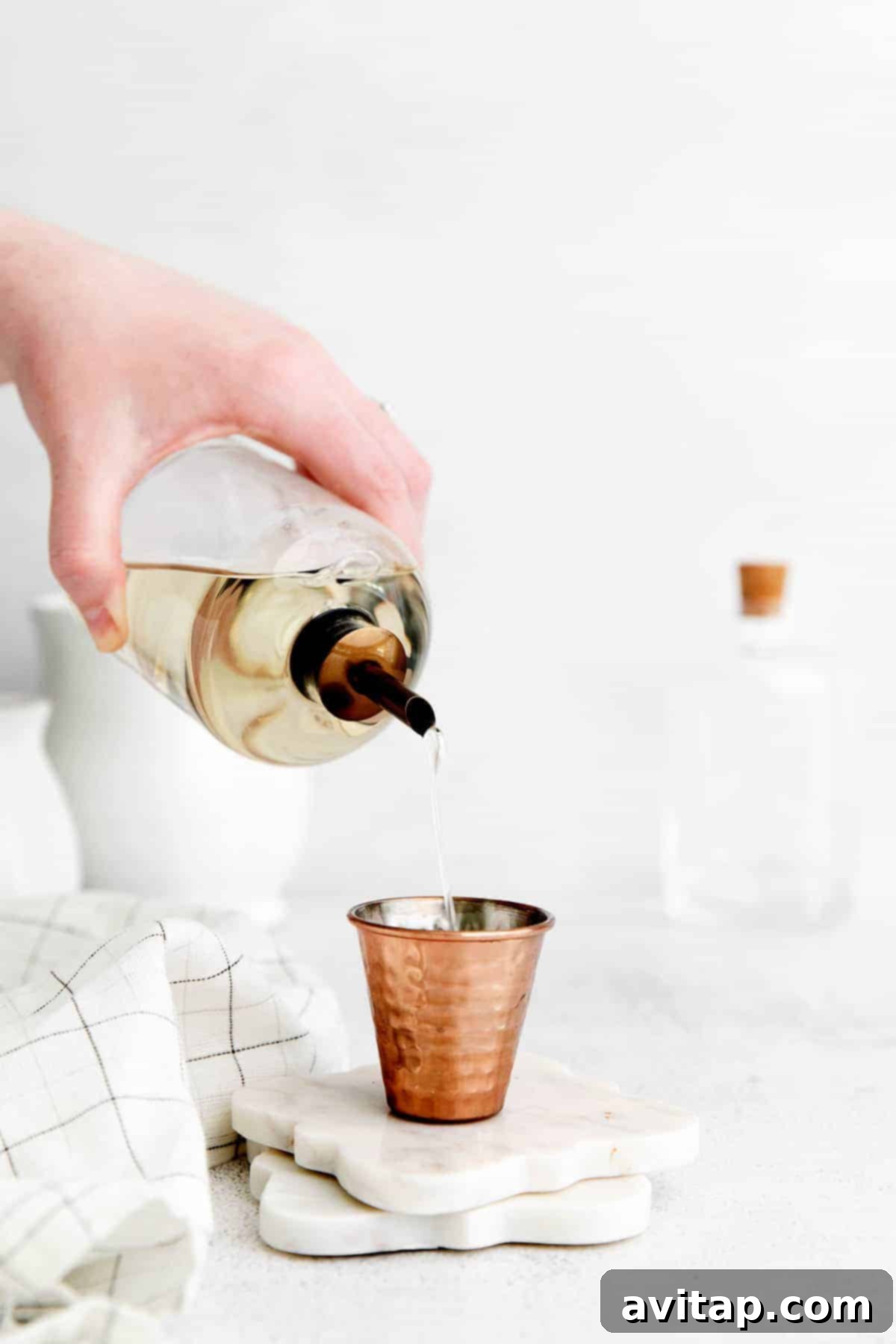 Freshly made simple syrup being poured into a shot glass, highlighting its smooth, clear consistency.