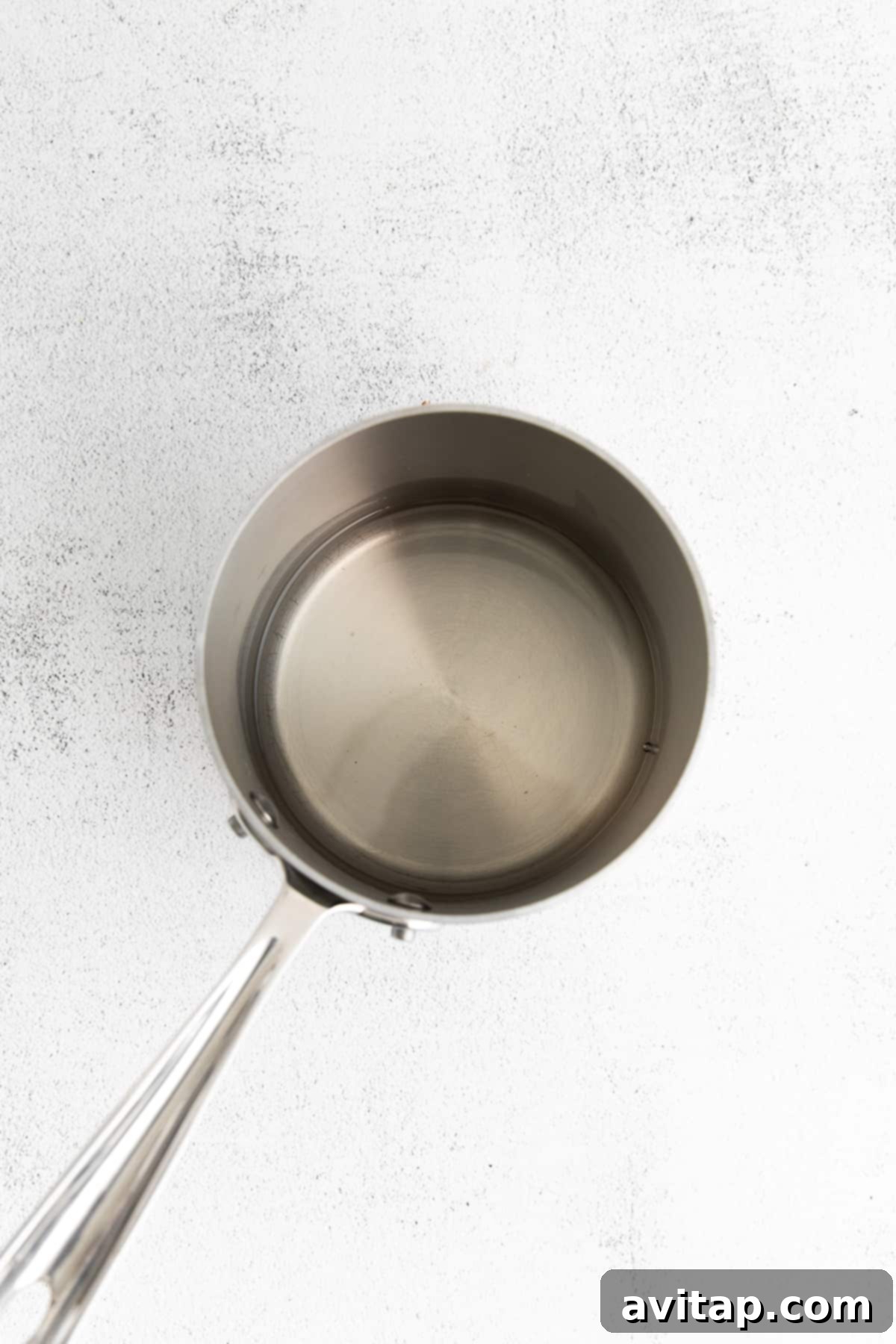 Simple syrup simmering gently in a saucepan on the stove, clear and ready for cooling.