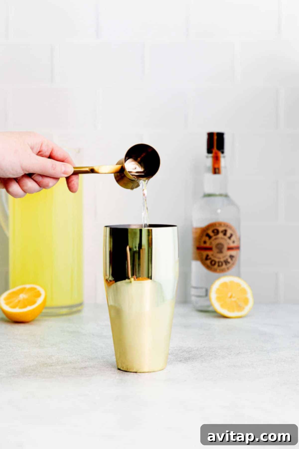 Adding vodka into a cocktail shaker, poised for mixing a delicious vodka lemonade.