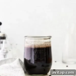 Cold brew coffee steeping in a jar with coffee grounds at the bottom.