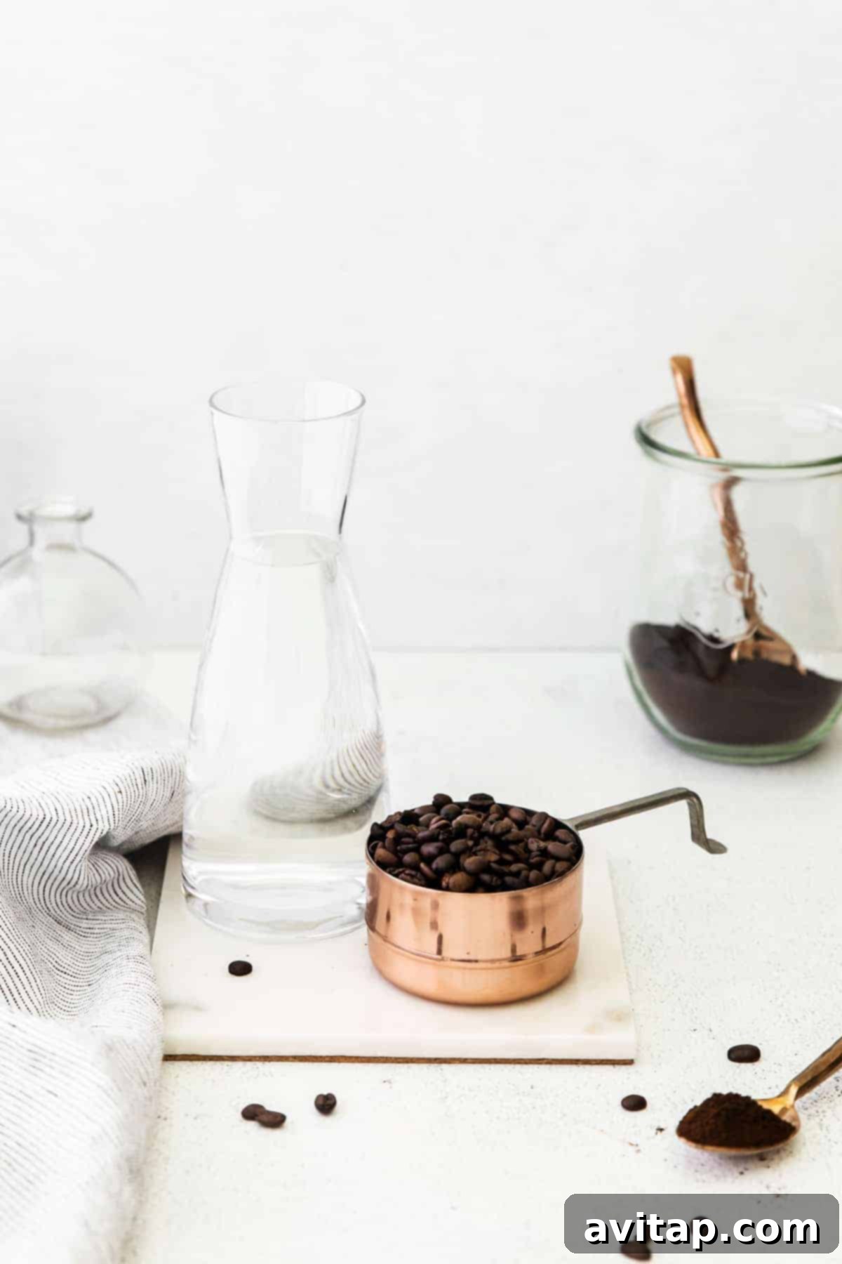 Cold brew coffee ingredients laid out on a table, including coffee beans, water, and a jar.