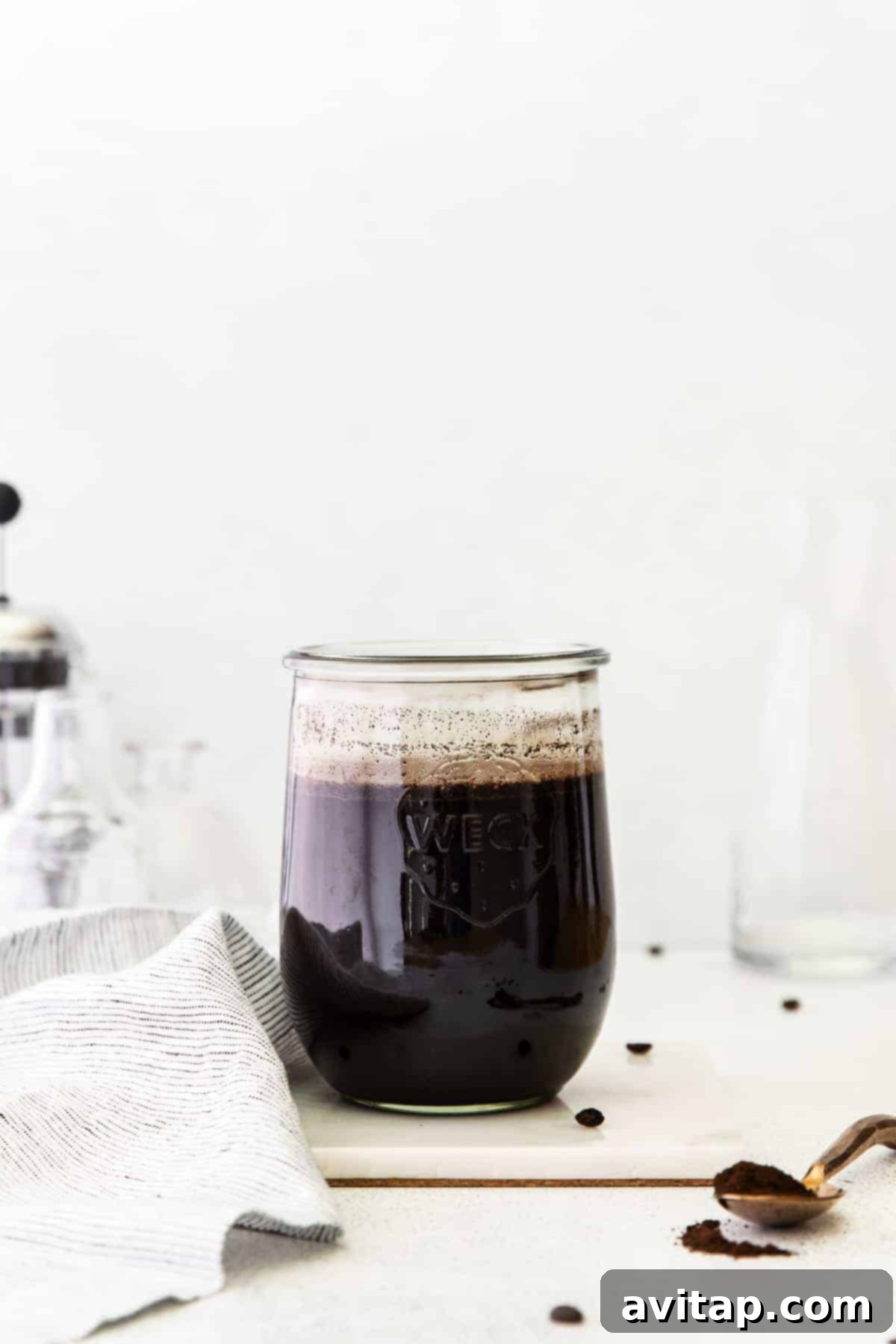 Cold brew coffee steeping in a jar with coffee grounds at the bottom.