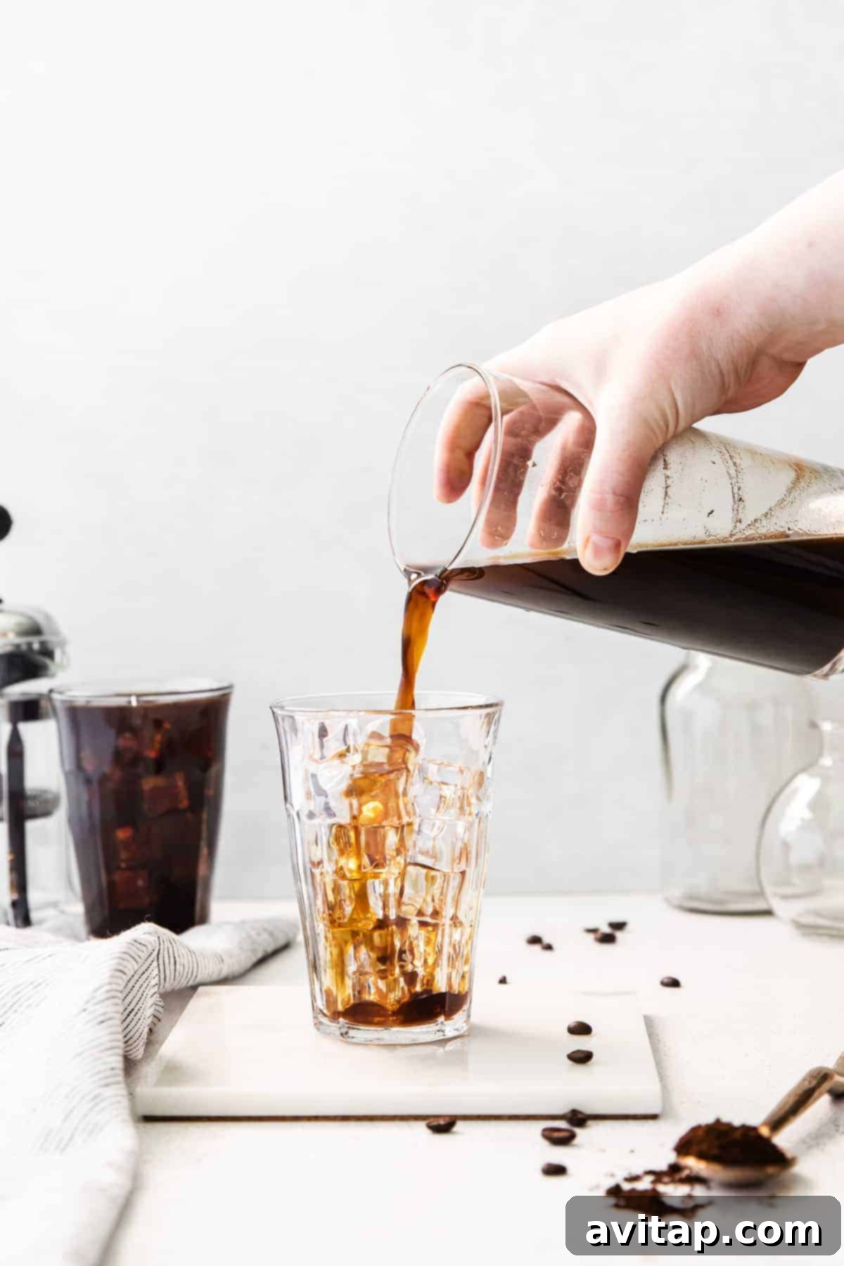 Pouring finished cold brew coffee into a glass filled with ice, ready to be enjoyed.