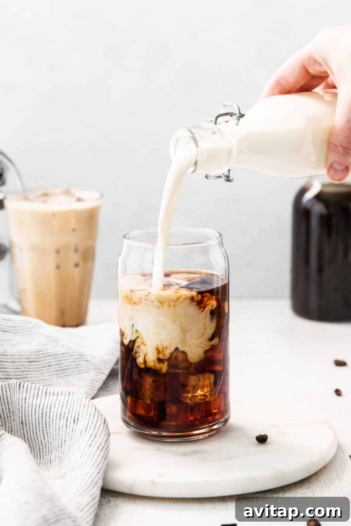 Velvet Vanilla Cold Brew 2 Pouring rich vanilla sweet cream into a glass of dark cold brew coffee over ice, creating a swirling effect.