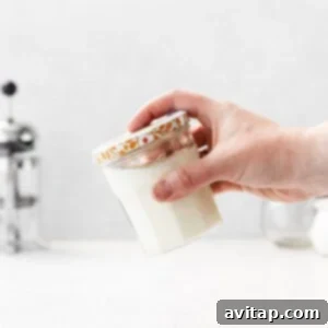 A person shaking a mason jar containing the sweet cream mixture, creating a frothy consistency.