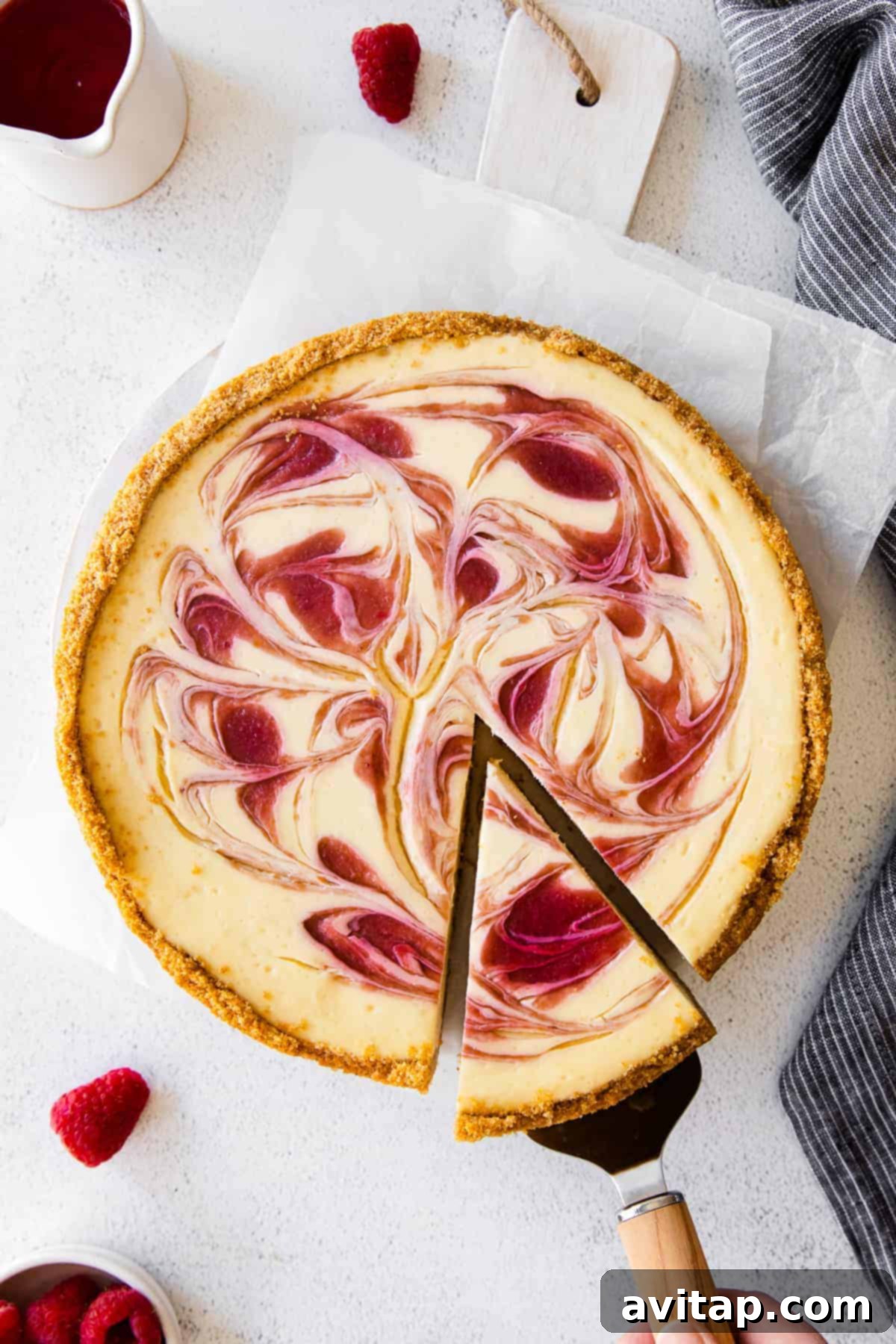 A beautifully sliced creamy Greek Yogurt Cheesecake with a luscious raspberry swirl on top, ready for serving.