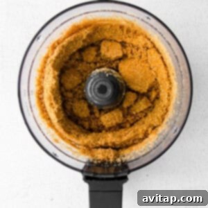 A food processor filled with graham cracker crumbs and butter, being prepared for a Greek yogurt cheesecake crust.