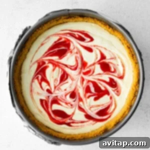 Greek yogurt cheesecake with red and white swirls on top, showing the marbled effect before baking.