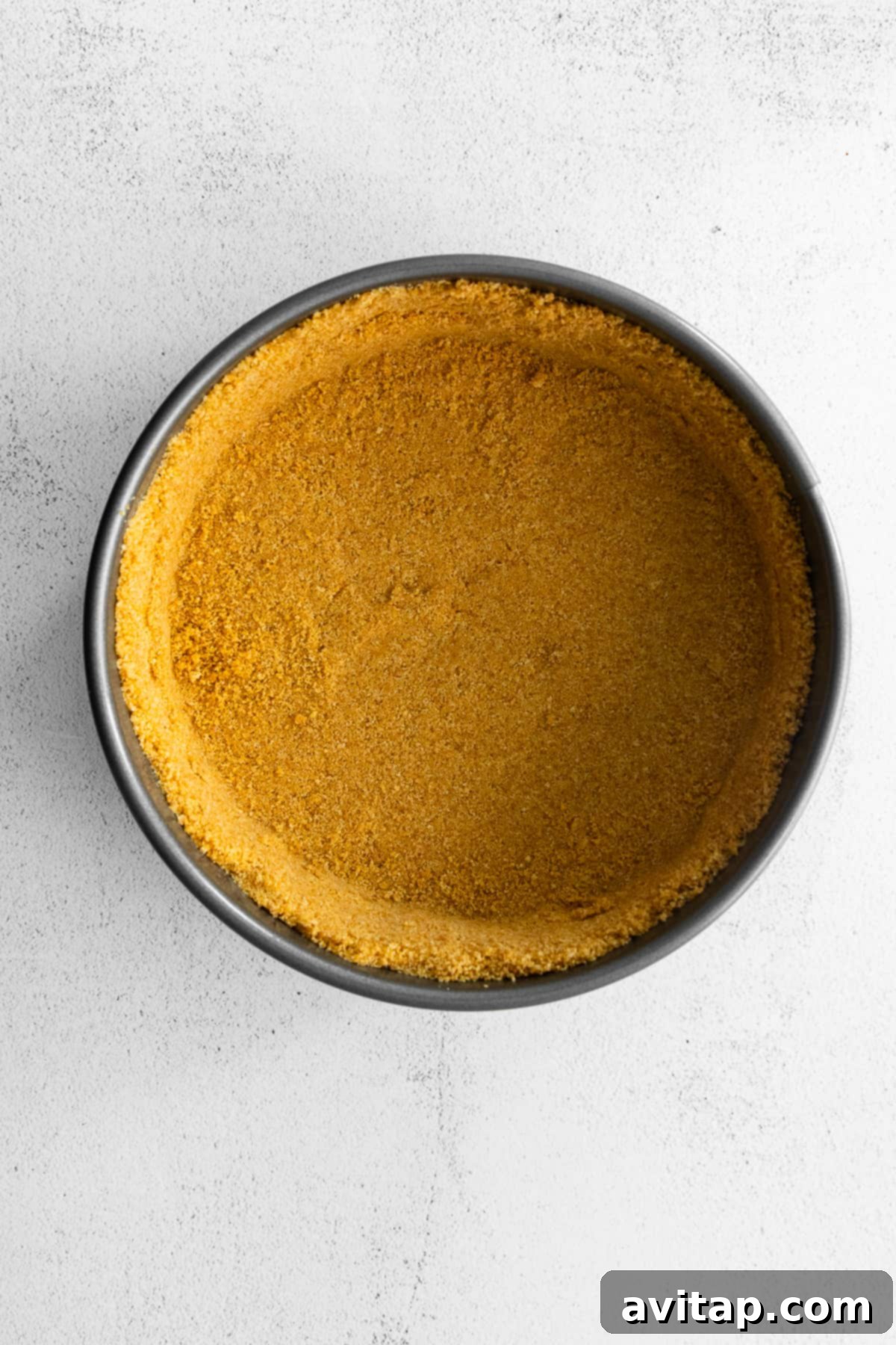 A perfectly formed graham cracker crust pressed into a springform pan, waiting for the delicious filling.