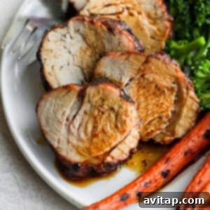 Effortless Pork Tenderloin Marinade 3 Sliced pork on a plate with broccoli and carrots, showcasing a delicious meal.