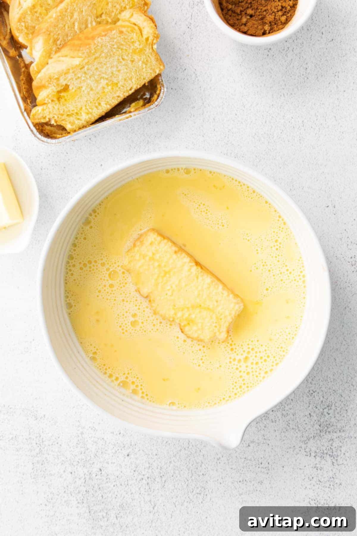 A slice of thick-cut bread soaking in the rich egg wash for French toast.
