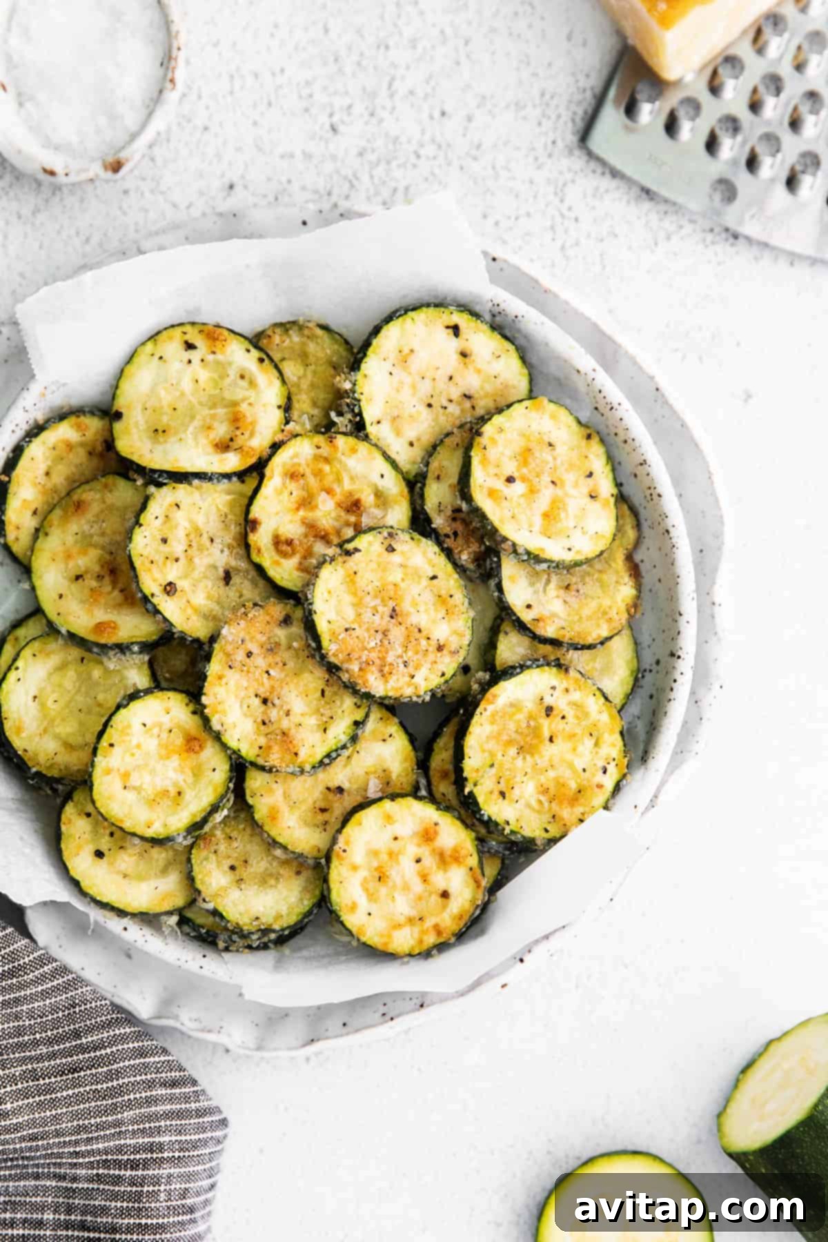 Golden Parmesan Zucchini 5 Fresh zucchini slices generously coated in a mixture of grated Parmesan cheese, salt, black pepper, and garlic powder, ready for baking.