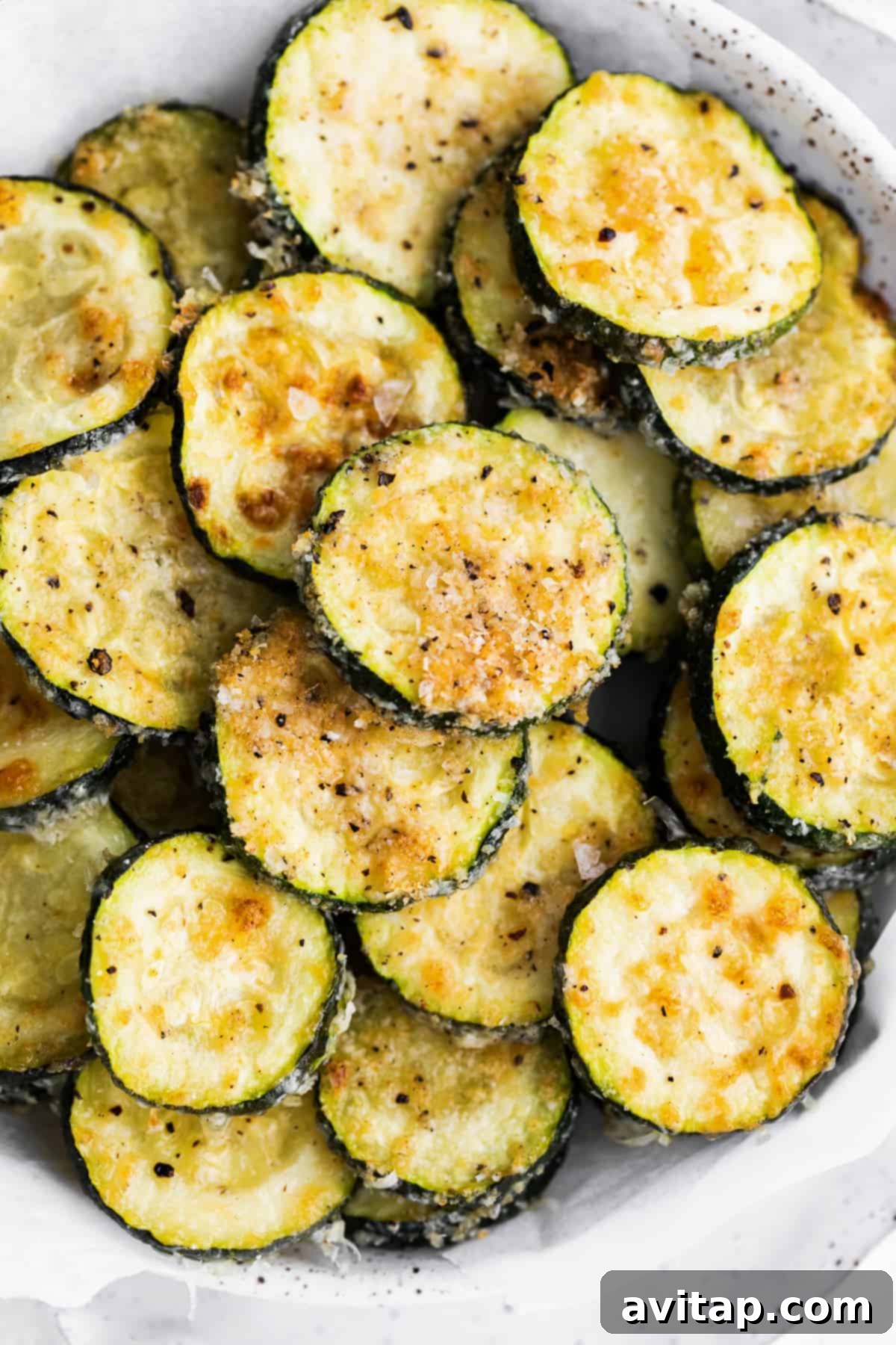 Golden Parmesan Zucchini 6 A large bowl filled with golden-brown Parmesan Baked Zucchini, garnished with fresh green herbs, ready to be enjoyed as a healthy snack or side dish.